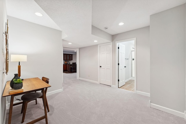 hallway with recessed lighting, light colored carpet, and baseboards