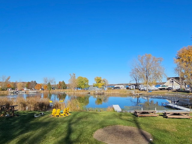 view of dock with a lawn and a water view