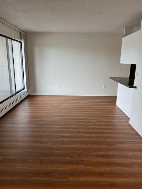 unfurnished living room featuring dark hardwood / wood-style floors and a textured ceiling