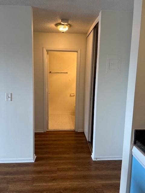 hall featuring dark wood-type flooring and a textured ceiling