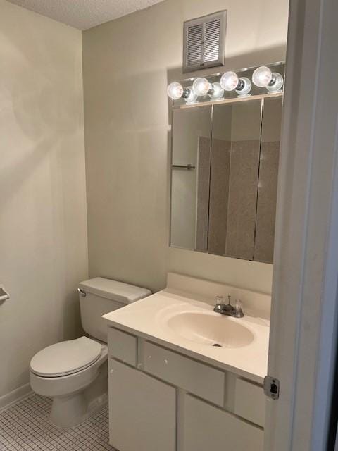 bathroom featuring tile patterned flooring, vanity, toilet, and a textured ceiling