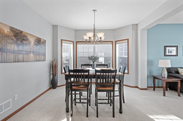 dining room with light carpet, a textured ceiling, and an inviting chandelier