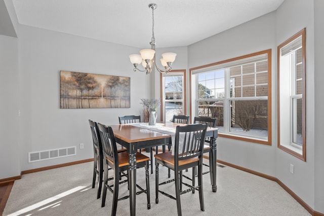 dining area with an inviting chandelier and light colored carpet