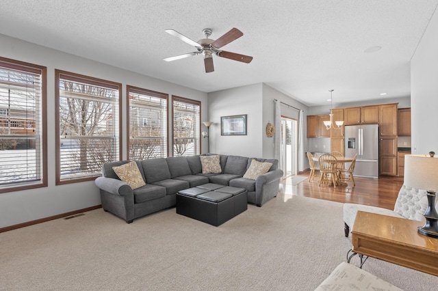 living room with ceiling fan, carpet floors, and a textured ceiling