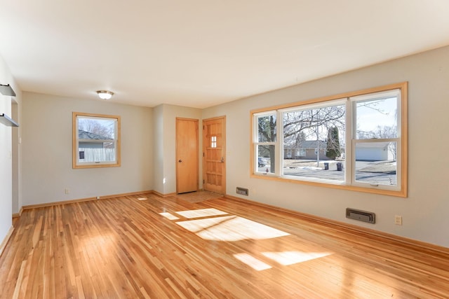 empty room with plenty of natural light, wood finished floors, and baseboards