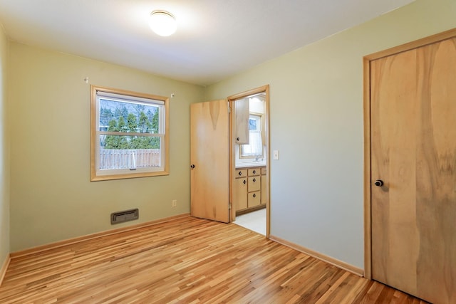 unfurnished bedroom featuring a closet, light wood-type flooring, and baseboards