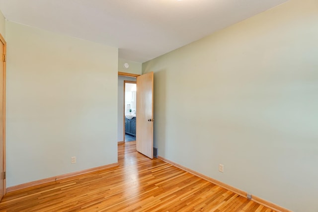 unfurnished room with baseboards and light wood-type flooring