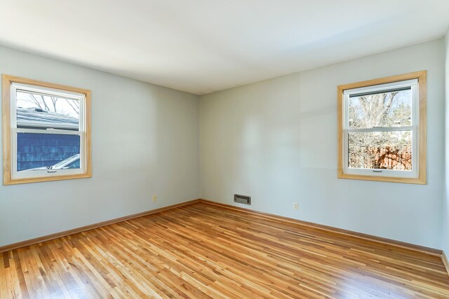 unfurnished room featuring light wood-type flooring, baseboards, and a healthy amount of sunlight