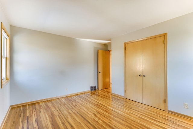 unfurnished bedroom featuring a closet, visible vents, baseboards, and light wood-style floors