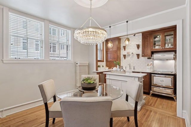 dining space with a notable chandelier, sink, and light wood-type flooring