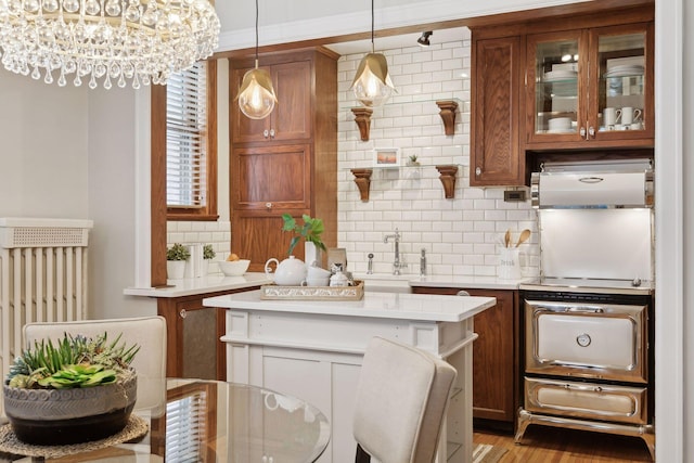 kitchen featuring sink, hanging light fixtures, a center island, decorative backsplash, and light wood-type flooring