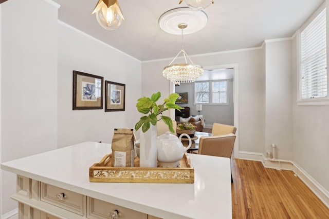 dining space featuring crown molding, a healthy amount of sunlight, an inviting chandelier, and light hardwood / wood-style floors