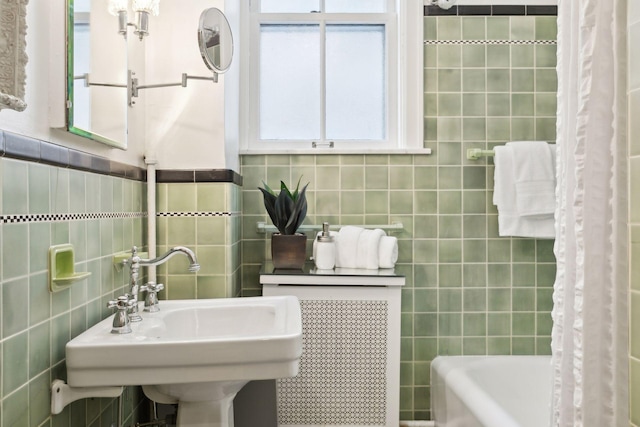 bathroom with shower / bath combination with curtain, sink, and tile walls