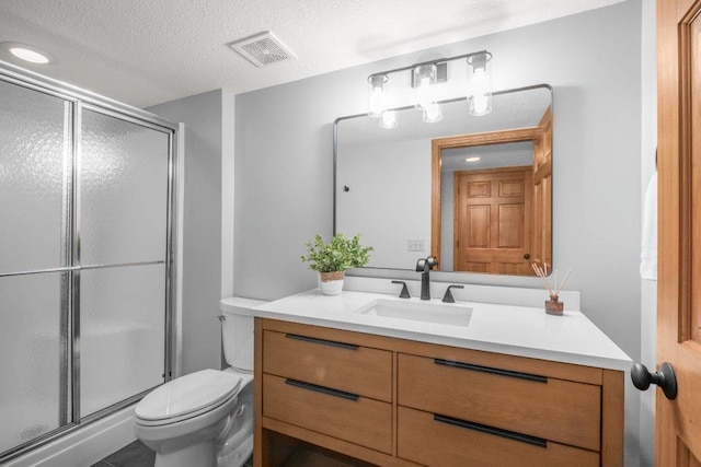 bathroom with an enclosed shower, vanity, a textured ceiling, and toilet