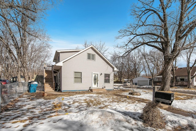 view of front facade featuring a detached garage, stairway, and fence