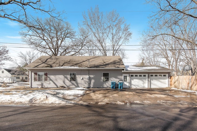 view of front of house with aphalt driveway, fence, and an attached garage