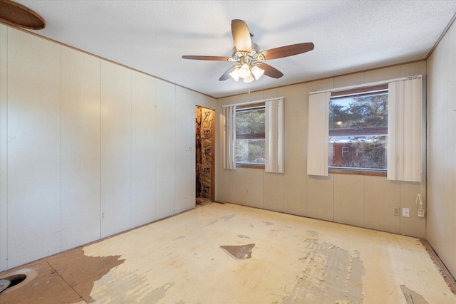 unfurnished room with a textured ceiling, a ceiling fan, and crown molding