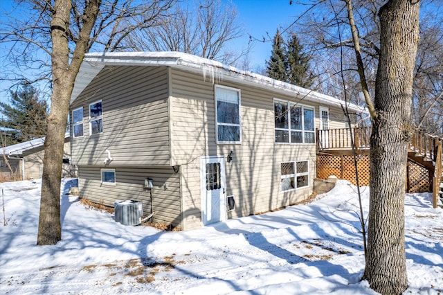 snow covered rear of property with central air condition unit and a deck