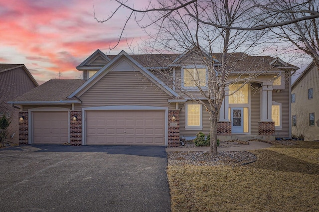 view of front of house with an attached garage, driveway, roof with shingles, and brick siding