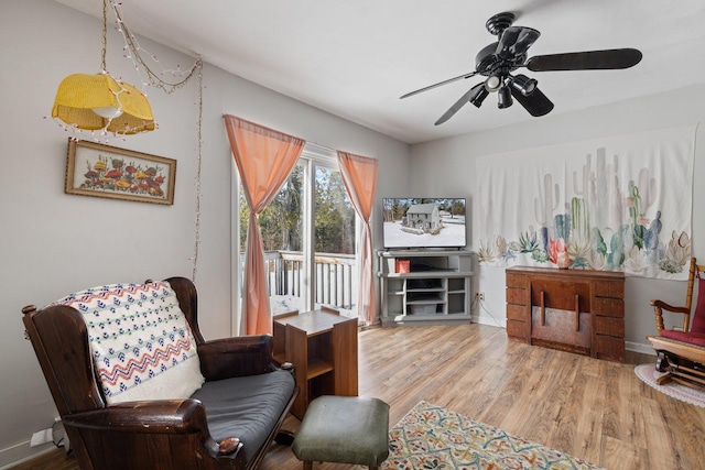 living area featuring ceiling fan, baseboards, and wood finished floors