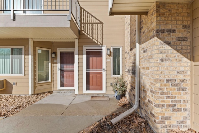 property entrance with brick siding and a balcony