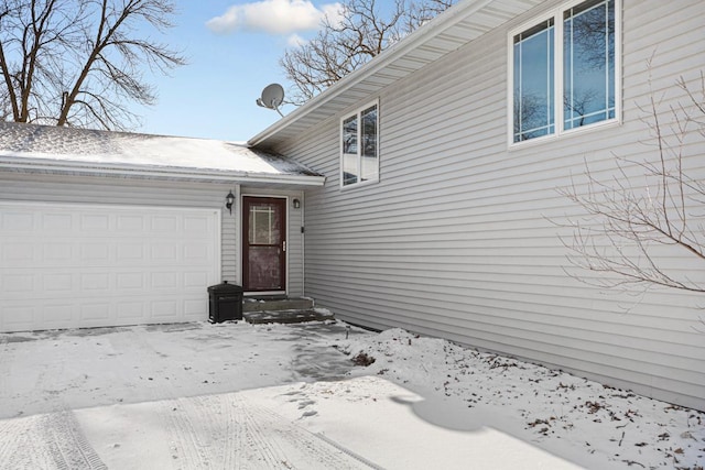 snow covered property entrance with a garage