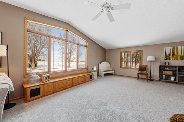 living area featuring light carpet, ceiling fan, vaulted ceiling, and a textured ceiling