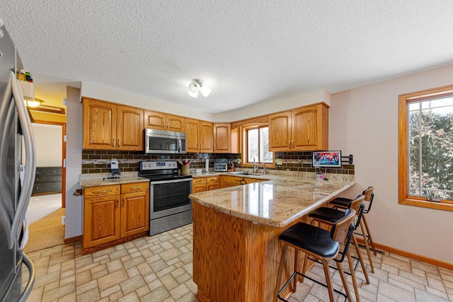 kitchen with backsplash, a kitchen breakfast bar, kitchen peninsula, and appliances with stainless steel finishes