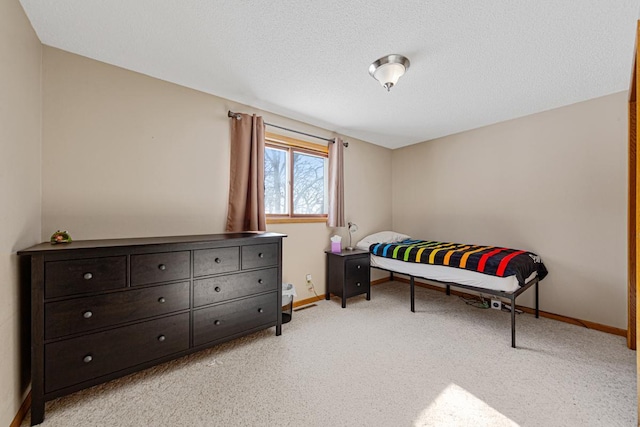 bedroom featuring light carpet and a textured ceiling