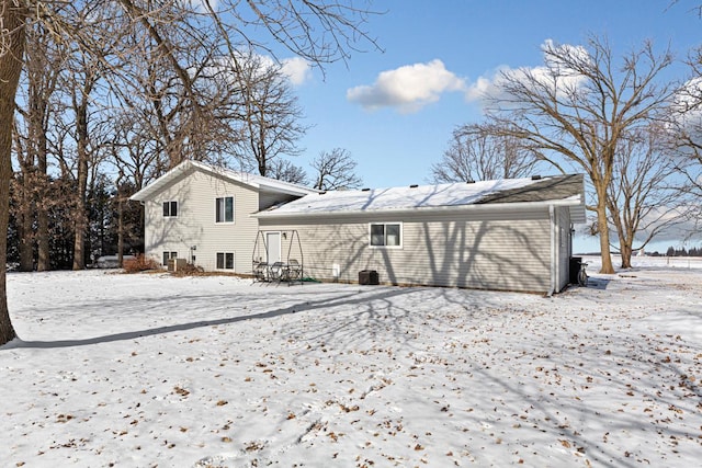 snow covered back of property featuring central AC unit