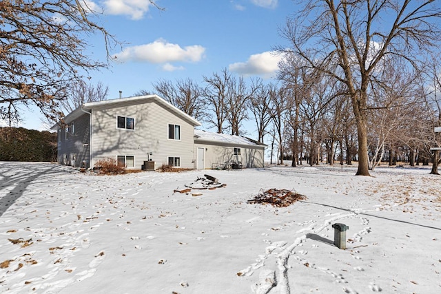 snow covered rear of property featuring central air condition unit