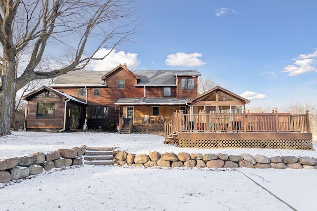 snow covered rear of property with a deck