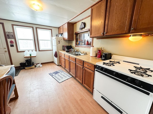 kitchen with sink, white appliances, and light wood-type flooring