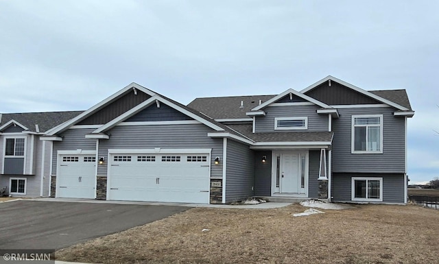 view of front of house with driveway, a garage, and roof with shingles