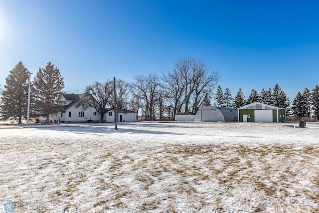 yard layered in snow featuring a garage and an outbuilding