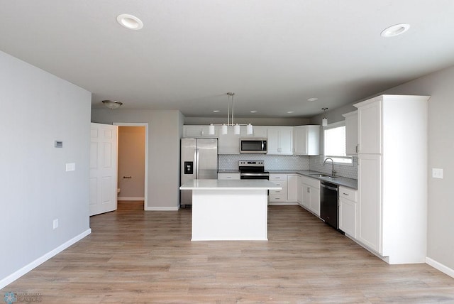 kitchen with pendant lighting, white cabinetry, a center island, and appliances with stainless steel finishes