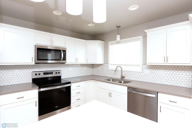 kitchen featuring sink, white cabinetry, decorative light fixtures, appliances with stainless steel finishes, and decorative backsplash