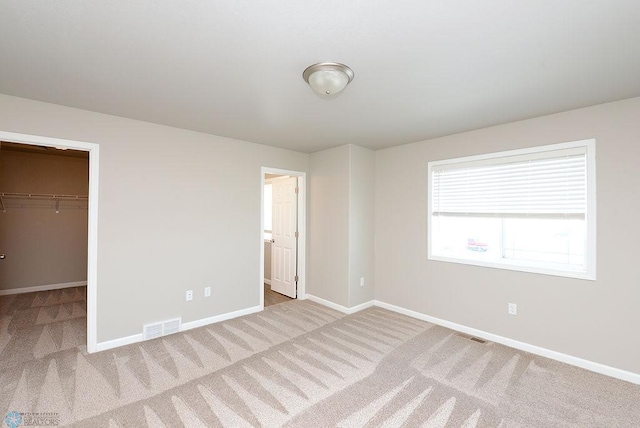 unfurnished bedroom featuring a closet, carpet flooring, and a spacious closet