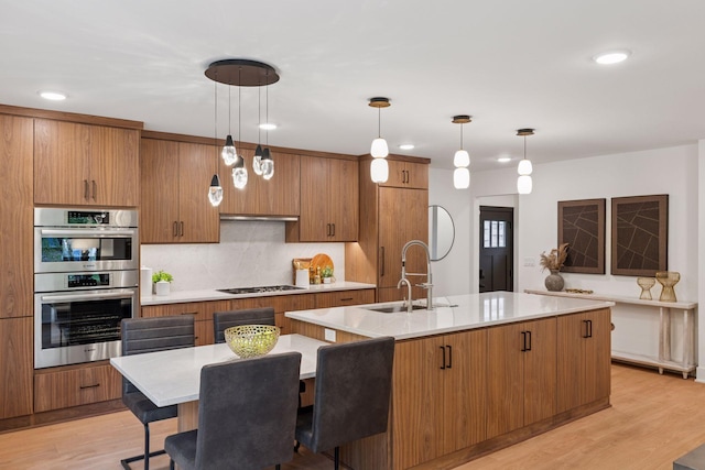 651 Sue Pl, Saint Paul, MN 55116 - kitchen featuring double oven, a sink, an island with sink, brown cabinetry, and light countertops