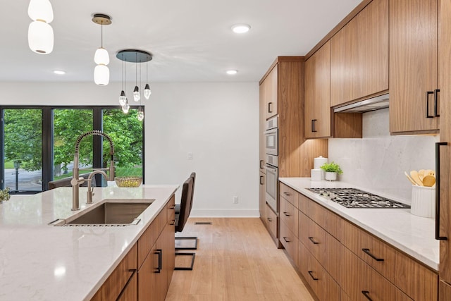 651 Sue Pl, Saint Paul, MN 55116 - kitchen featuring a sink, stainless steel appliances, backsplash, light wood-style flooring, and light stone counters