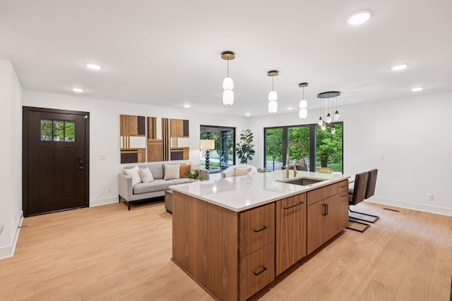 651 Sue Pl, Saint Paul, MN 55116 - kitchen featuring a sink, recessed lighting, light countertops, light wood-style flooring, and a kitchen island with sink