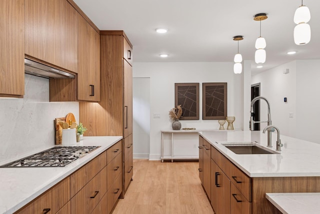 651 Sue Pl, Saint Paul, MN 55116 - kitchen featuring stainless steel gas stovetop, a sink, light wood finished floors, brown cabinets, and hanging light fixtures