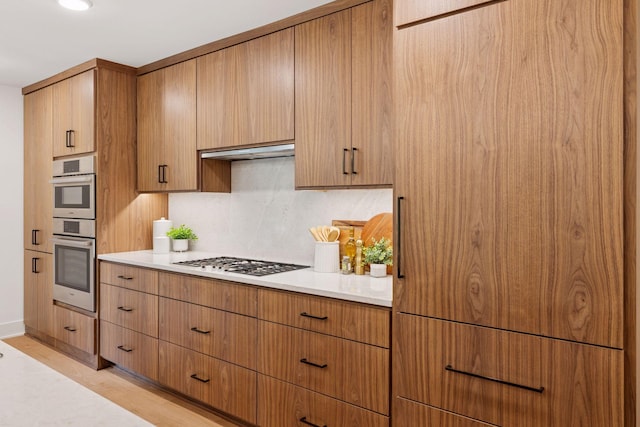 651 Sue Pl, Saint Paul, MN 55116 - kitchen with gas stovetop, stainless steel double oven, light countertops, tasteful backsplash, and light wood-style floors