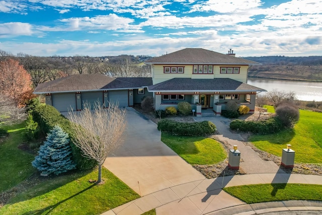 view of front facade featuring a shingled roof, a water view, a front yard, driveway, and an attached garage