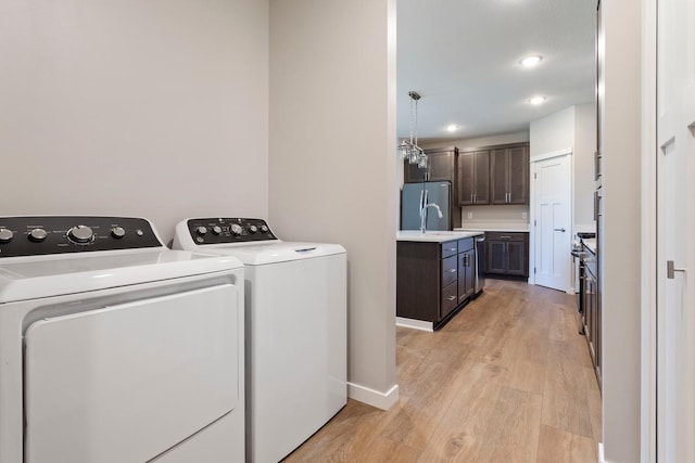 clothes washing area featuring washer and clothes dryer and light wood-type flooring