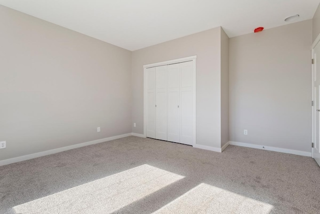 unfurnished bedroom featuring light colored carpet and a closet