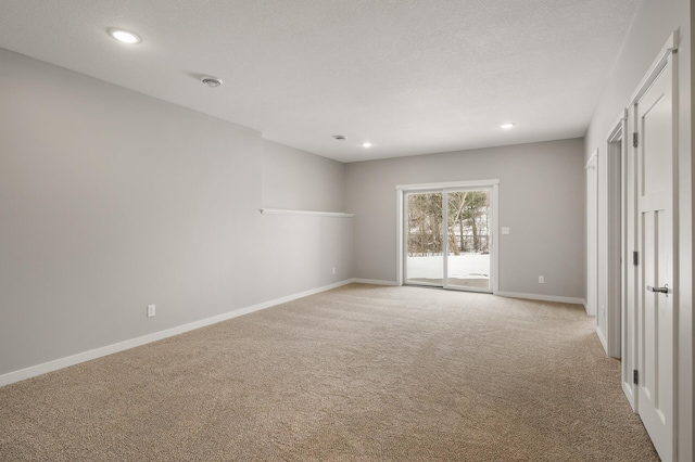 spare room featuring light colored carpet and a textured ceiling