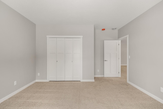 unfurnished bedroom featuring light carpet and a closet