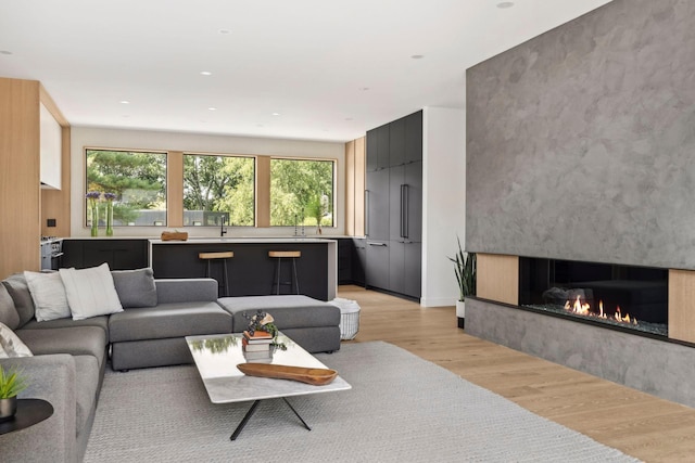 living room with a high end fireplace and light hardwood / wood-style flooring