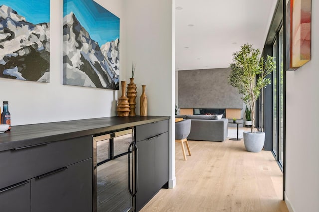 hallway with wine cooler, a wall of windows, and light hardwood / wood-style flooring